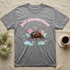 Madagascar Hissing Cockroach Baby T-Shirt in Sport Grey — Pastel Madagascar hissing cockroach among leaves, mushroom and moss, puffy pink wordmark "just misunderstood" above.