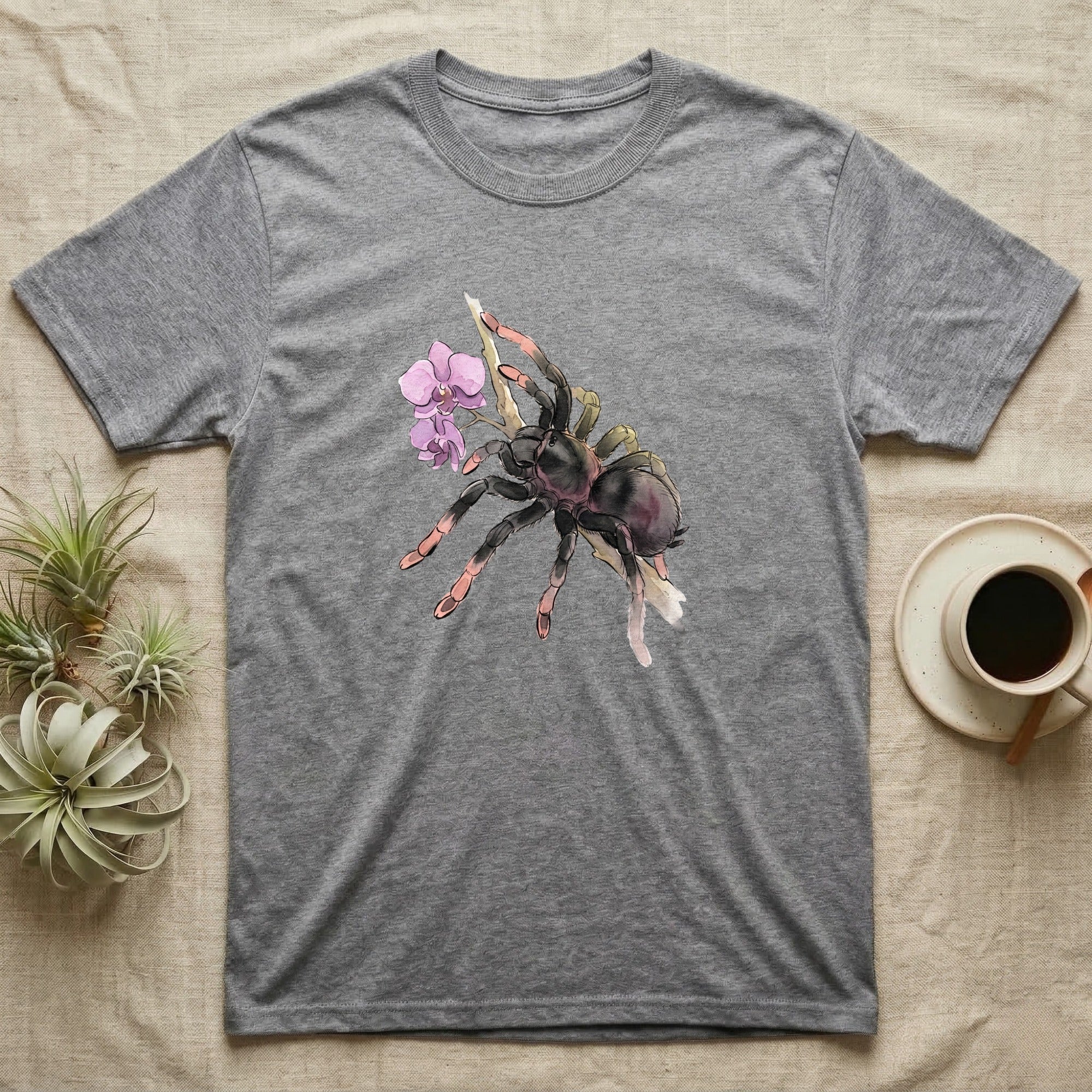 Pink-Toe Tarantula Blossom T-Shirt in Sport Grey — Watercolor illustration of a charcoal pink-toe tarantula with salmon toe tips holding an orchid blossom sprig, on a dark grey t-shirt.