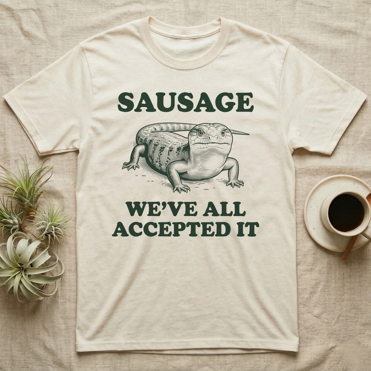 Blue Tongue Skink Sausage T-Shirt in Natural — Antique-engraved blue-tongued skink facing forward, with the word SAUSAGE above and a two-line caption below.