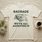 Blue Tongue Skink Sausage T-Shirt in Natural — Antique-engraved blue-tongued skink facing forward, with the word SAUSAGE above and a two-line caption below.