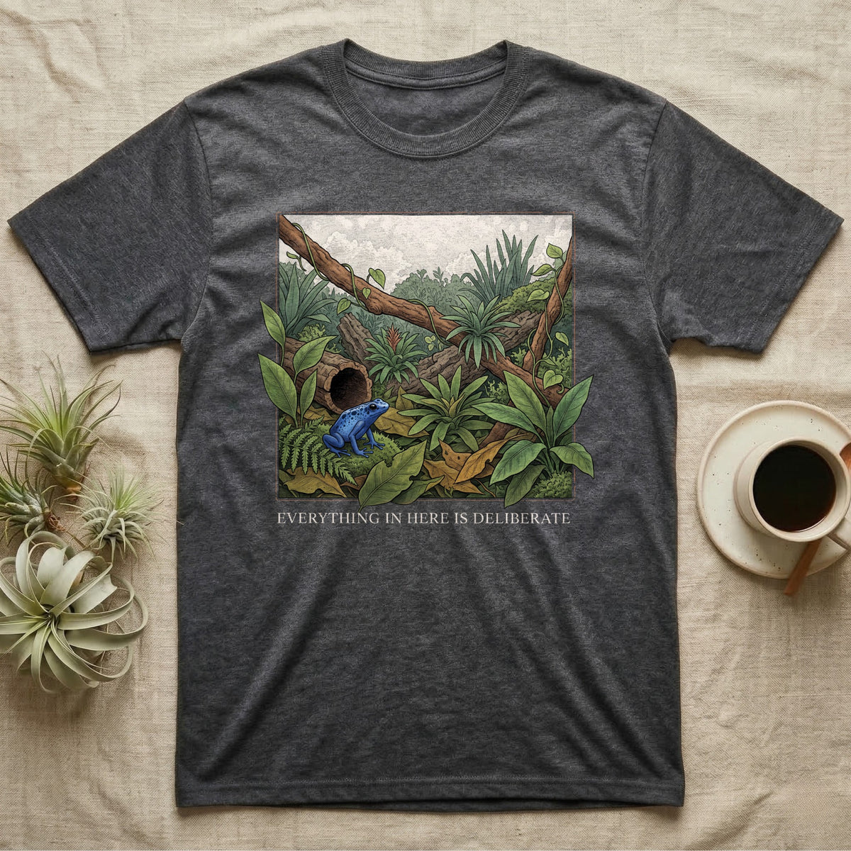 Dart Frog Bioactive Vivarium T-Shirt in Dark Heather — Illustrated panel of a cobalt dart frog in a layered planted vivarium, leaves crossing the inked border.