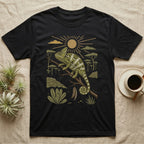 Veiled Chameleon Home Range T-Shirt in Black — Woodcut-style illustration of a veiled chameleon gripping an acacia branch with terraced walls and umbrella trees behind, no on-shirt text.