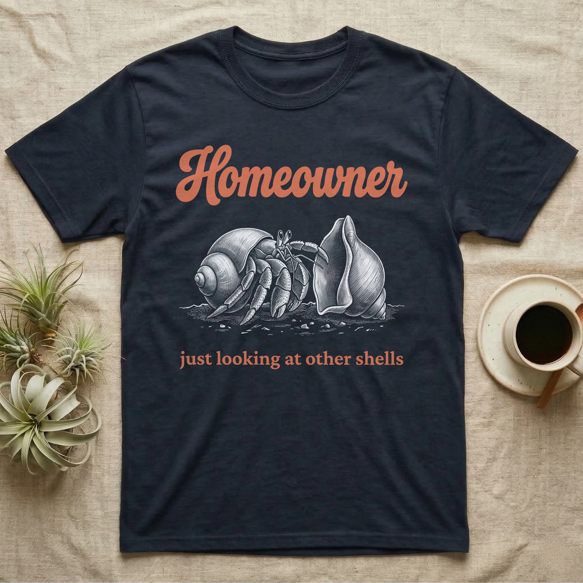 Hermit Crab Homeowner T-Shirt in Navy — White-line engraving of a land hermit crab eyeing a bigger empty shell, under orange script Homeowner and a serif line