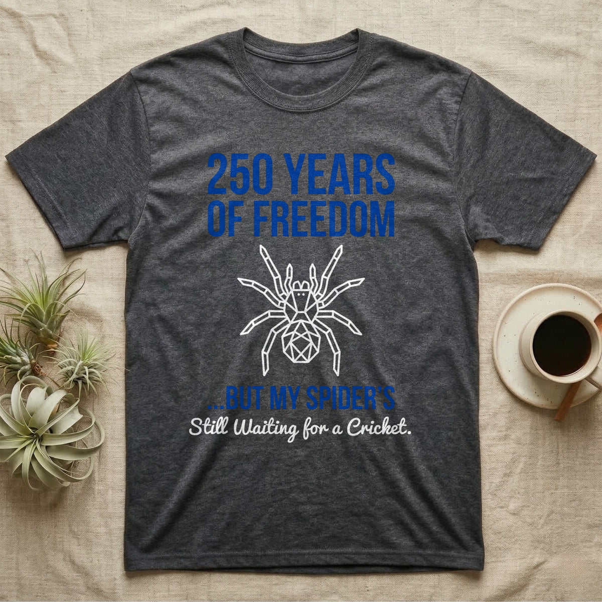 Tarantula Waiting For Cricket Tee in Dark Heather — Minimalist geometric tee with a low-poly white tarantula and blue text reading 250 Years Of Freedom but my spider's still waiting for a cricket.
