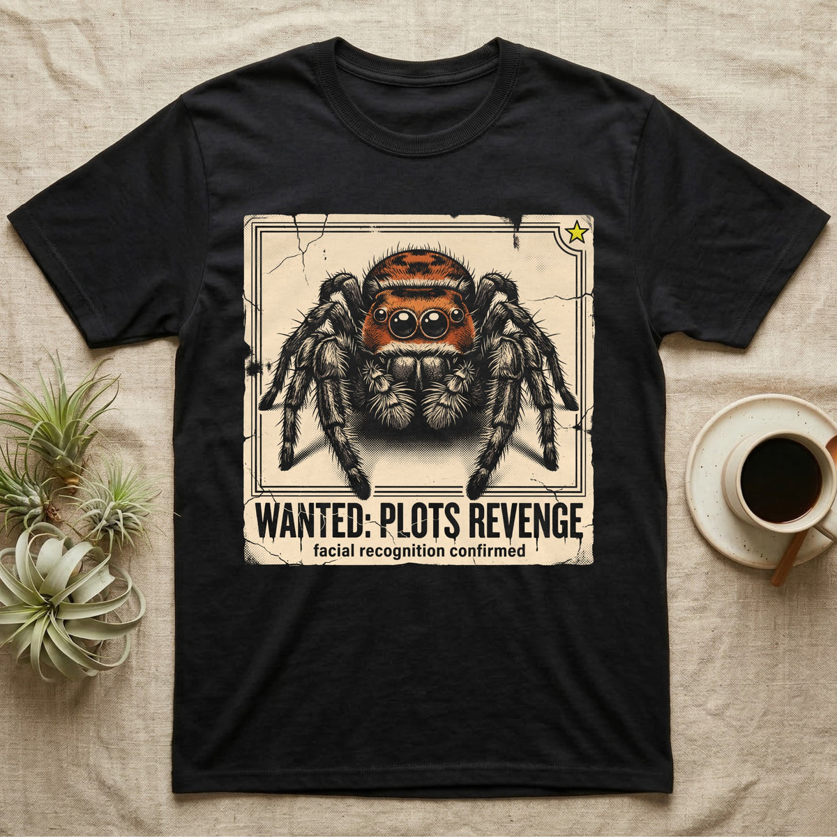 Jumping Spider Wanted T-Shirt in Black — Distressed wanted-poster illustration of a front-facing jumping spider with the banner text plots revenge below.