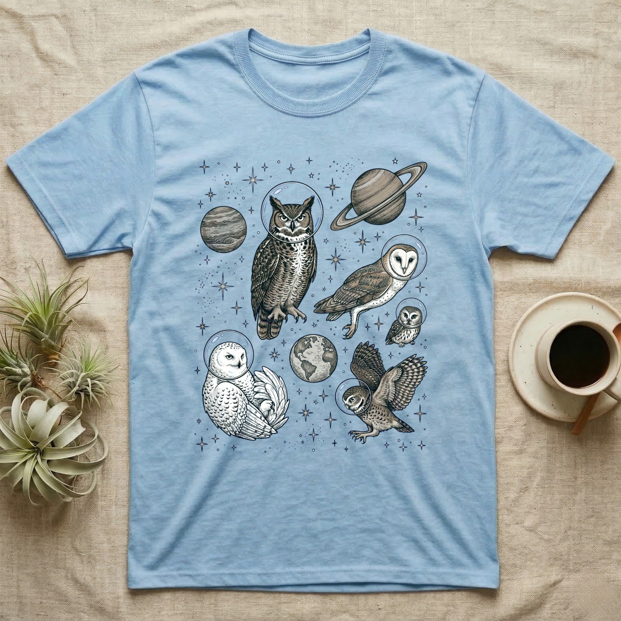 Light blue t-shirt with owls in space illustration, wearing astronaut helmets.