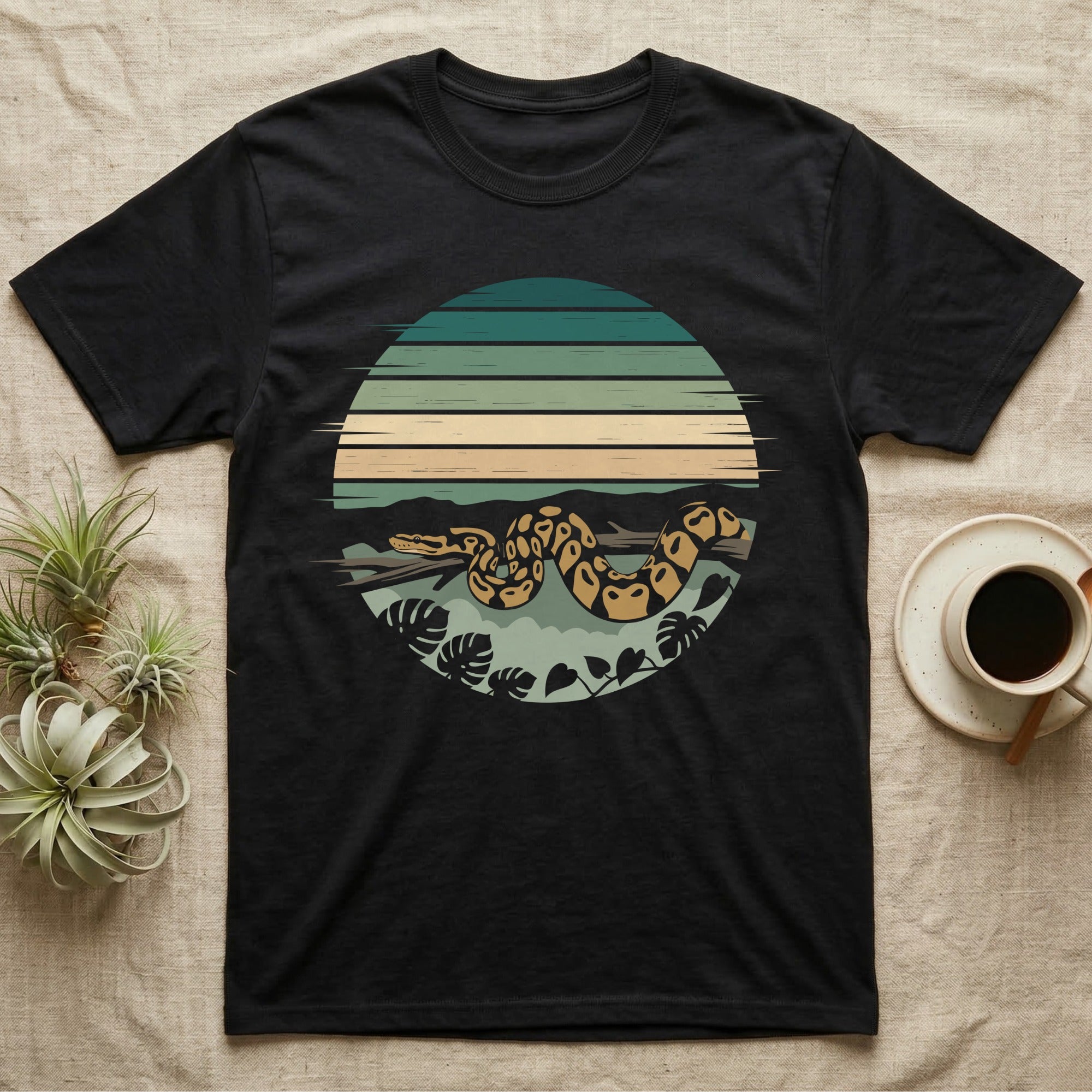 Ball Python Monstera T-Shirt in Black — Ball python coiled through a striped rainforest circle window with monstera and pothos on a near-black tee