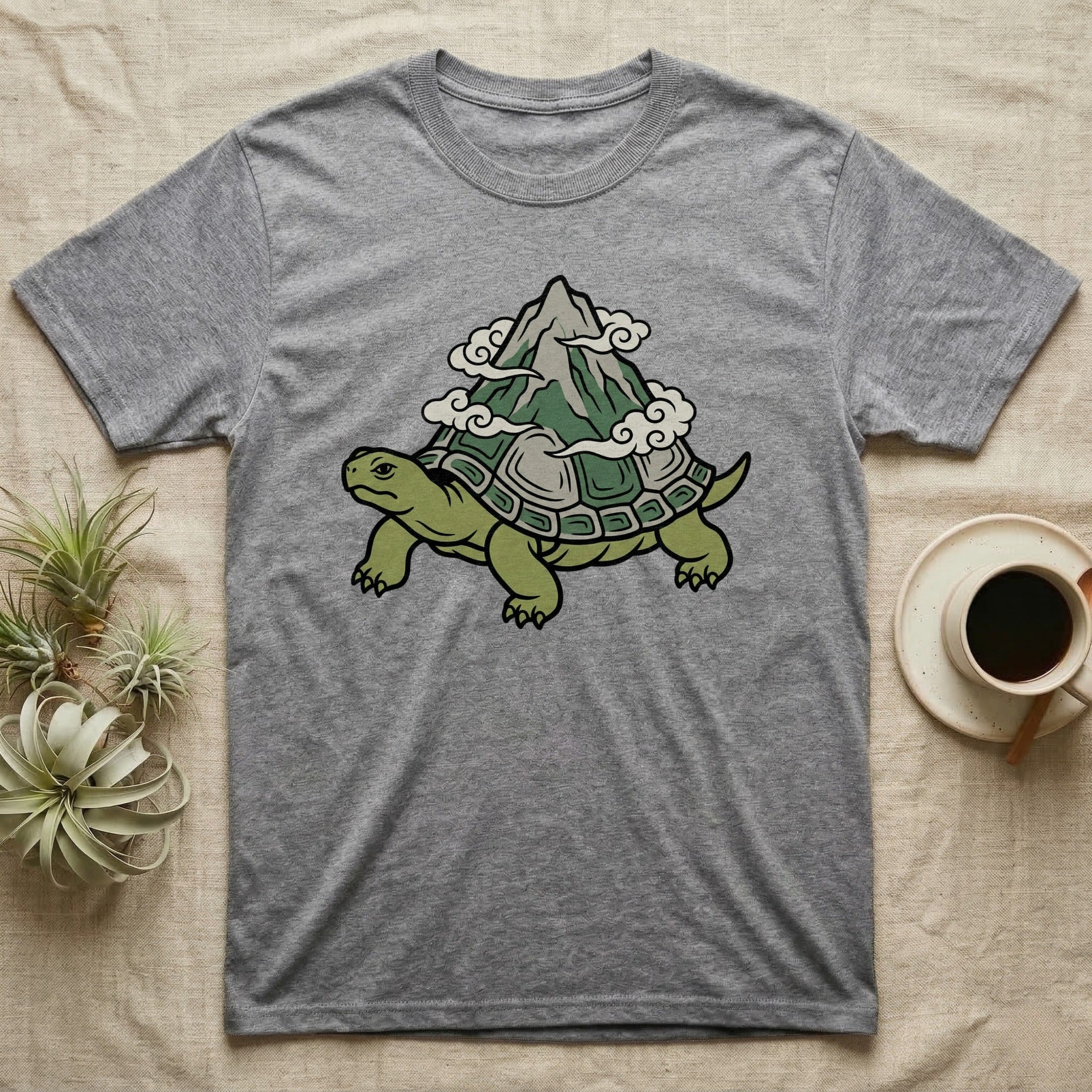 Grey t-shirt with a cartoon turtle carrying a mountain on its shell.