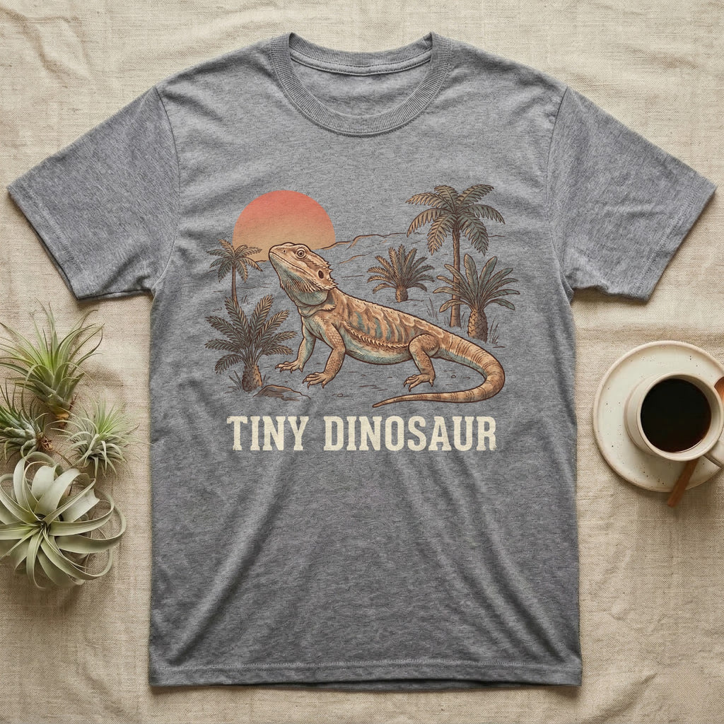 Tiny Dinosaur Bearded Dragon T-Shirt in Sport Grey — Retro natural-history illustration of a bearded dragon in profile in a prehistoric landscape with a distressed "Tiny Dinosaur" caption.