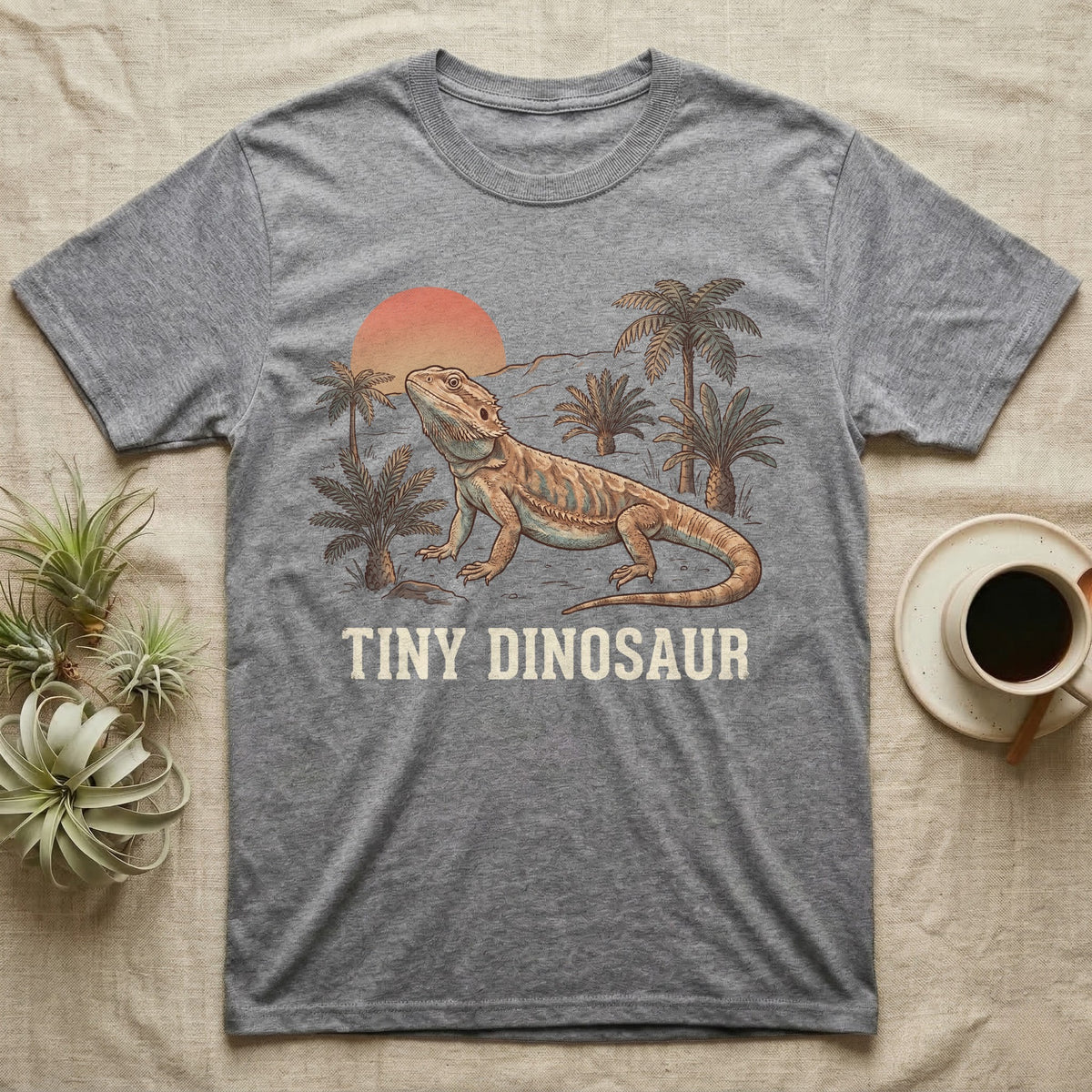 Tiny Dinosaur Bearded Dragon T-Shirt in Sport Grey — Retro natural-history illustration of a bearded dragon in profile in a prehistoric landscape with a distressed "Tiny Dinosaur" caption.