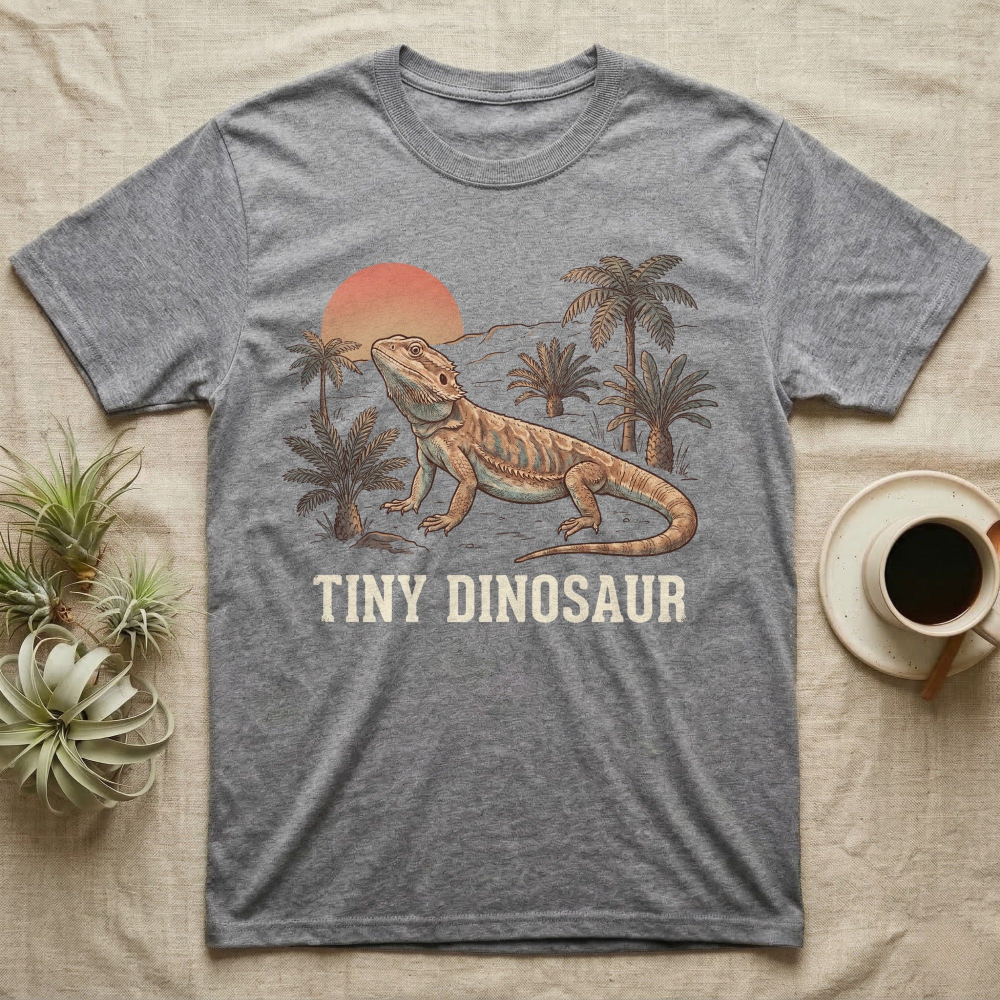 Tiny Dinosaur Bearded Dragon T-Shirt in Sport Grey — Retro natural-history illustration of a bearded dragon in profile in a prehistoric landscape with a distressed "Tiny Dinosaur" caption.