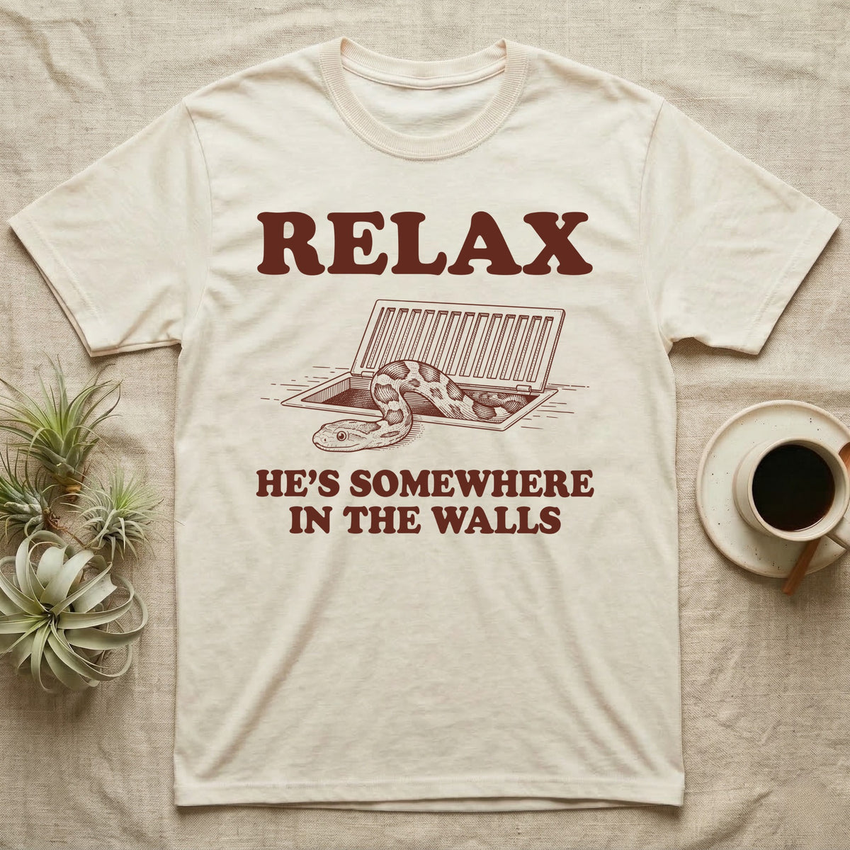 Corn Snake Walls T-Shirt in Natural — Engraved corn snake looking out of an open floor vent, with the words Relax, He's Somewhere in the Walls