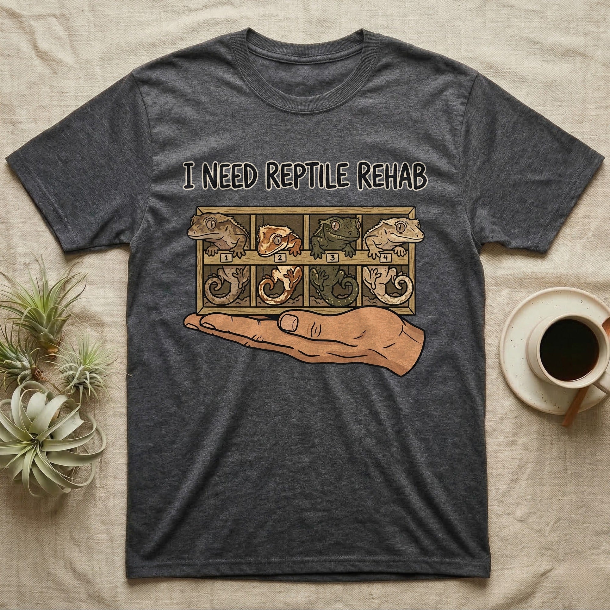 Crested Gecko Rehab T-Shirt in Dark Heather — Vector scene of a hand presenting a rack of four crested geckos under a marker-style reptile rehab caption.
