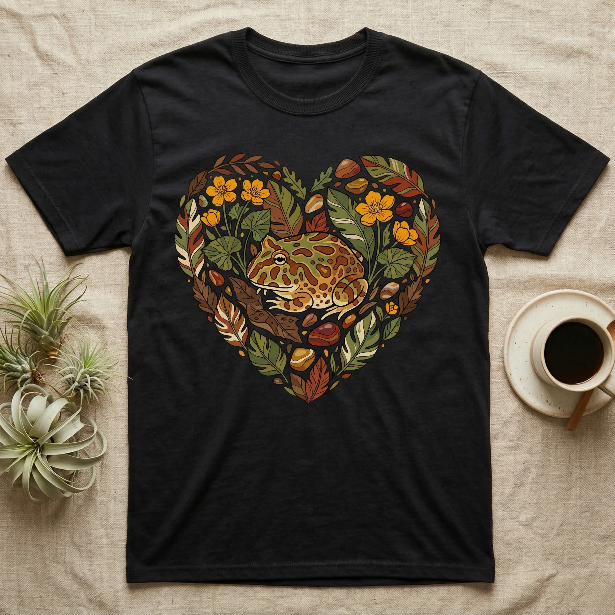 Black t-shirt with a heart-shaped graphic of a frog surrounded by leaves and stones.