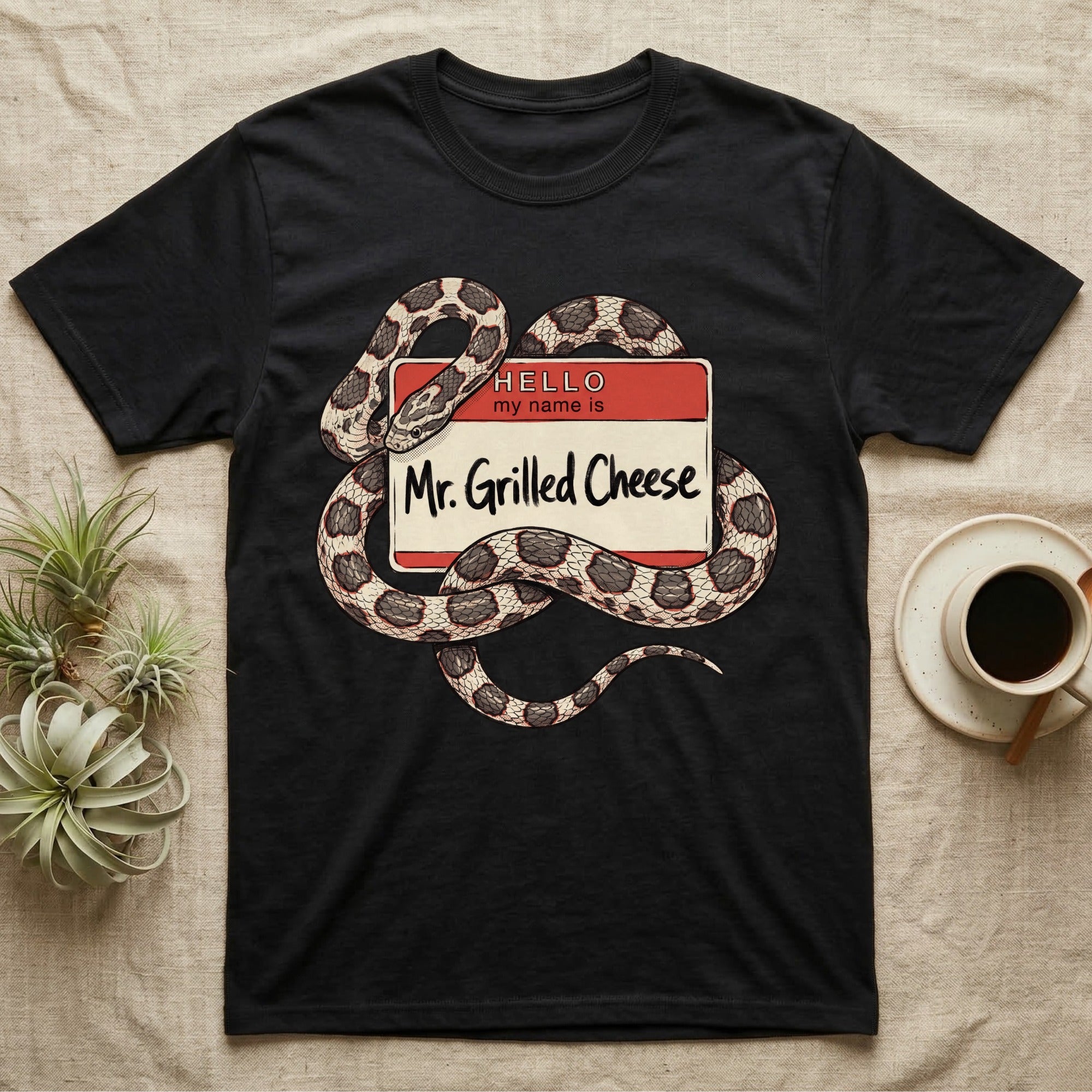 Grilled Cheese Corn Snake T-Shirt in Black — Flat retro illustration of a corn snake coiled through a "Hello my name is Mr. Grilled Cheese" name-tag badge.