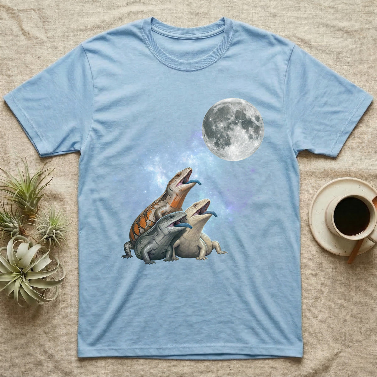 Blue-Tongued Skink Moon Howl T-Shirt in Light Blue — Three Blue-Tongued Skink colour morphs howling at a full moon over a nebula on a dark grey t-shirt.
