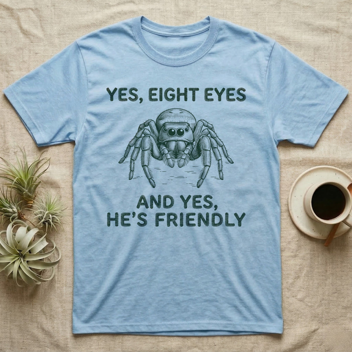 Jumping Spider Eight Eyes T-Shirt in Light Blue — Engraved jumping spider head-on with large forward eyes, between stitch-look lettering on grey.