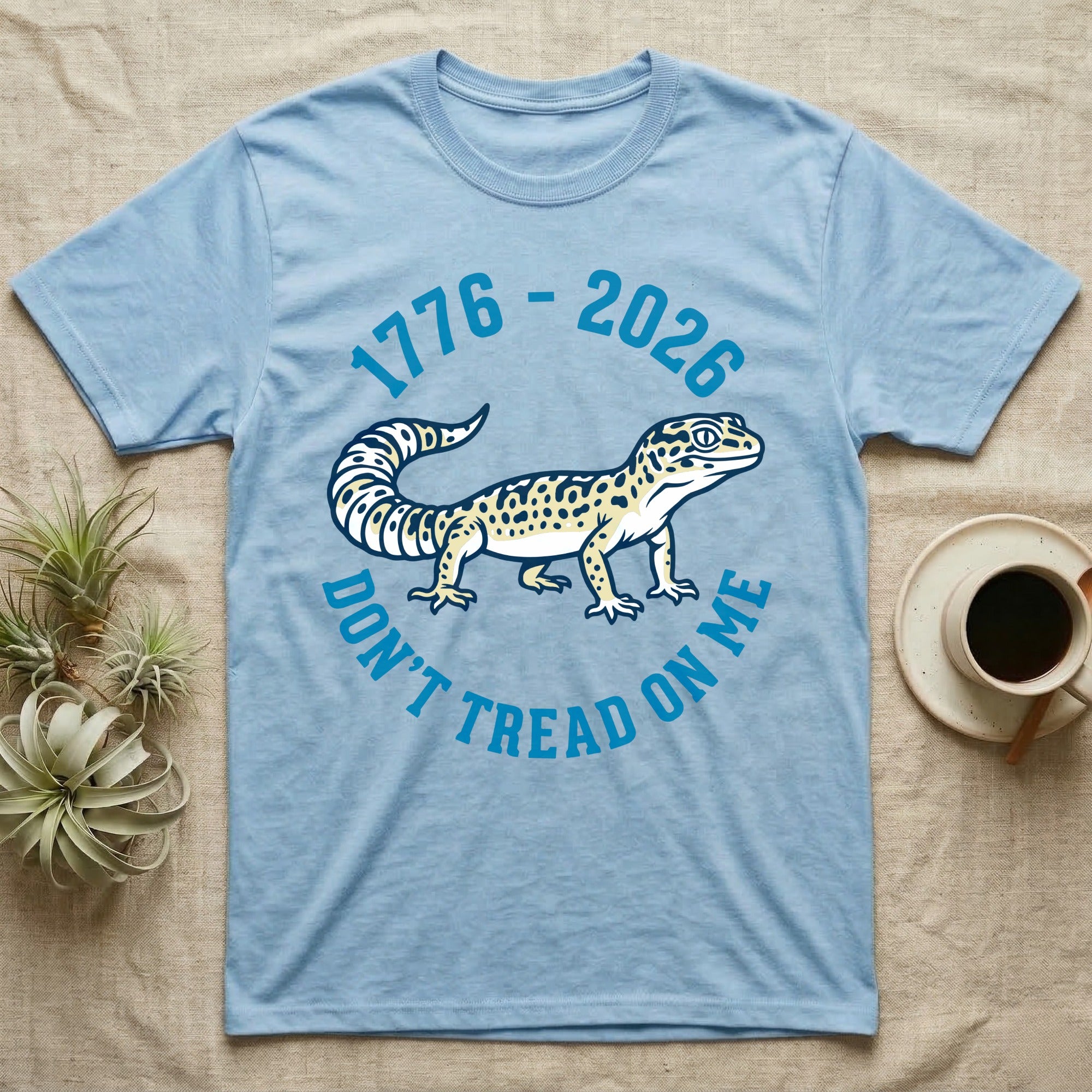 Leopard Gecko 1776 T-Shirt in Light Blue — Two-colour vector leopard gecko in profile ringed by arched text reading 1776 to 2026 and Don't Tread On Me.
