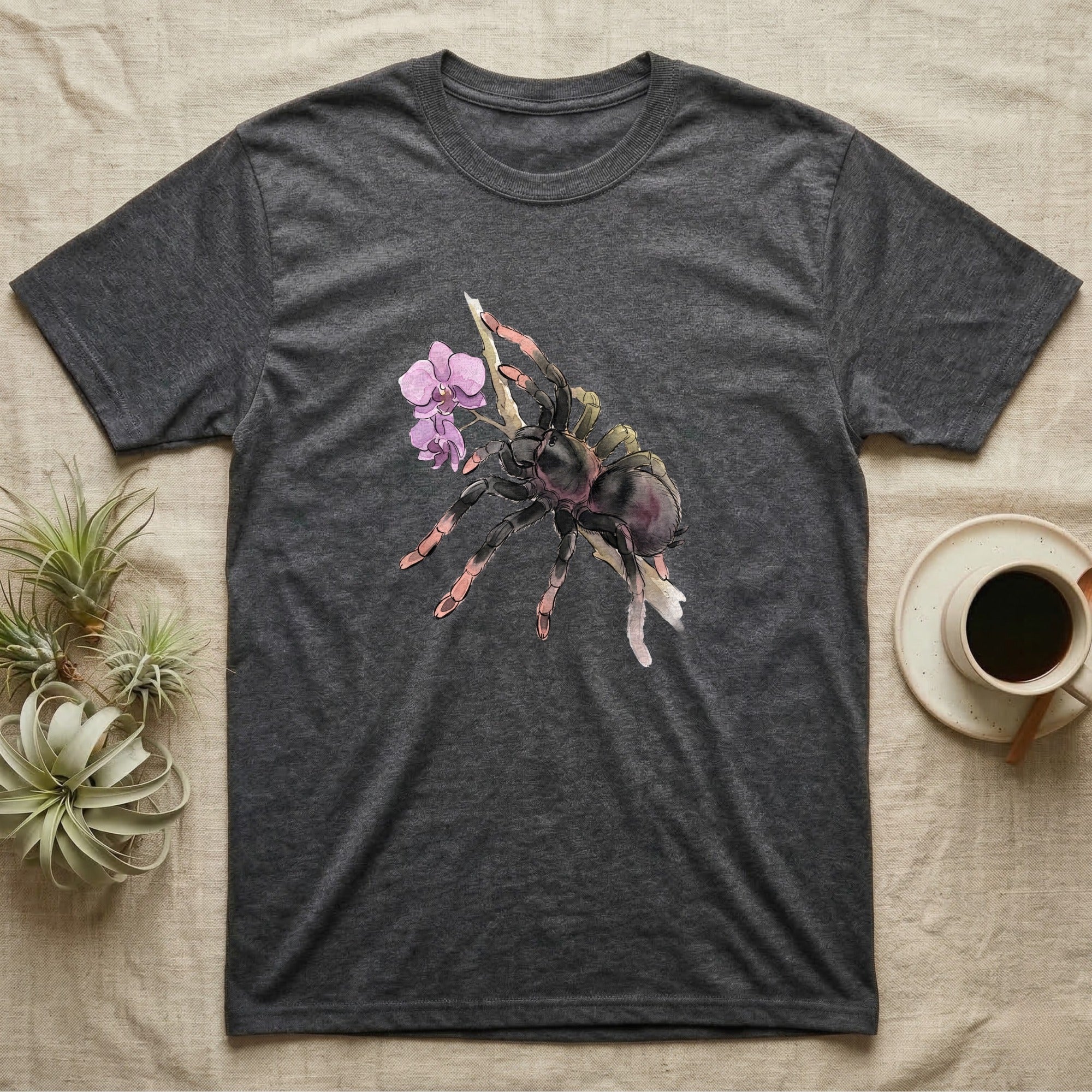Pink-Toe Tarantula Blossom T-Shirt in Dark Heather — Watercolor illustration of a charcoal pink-toe tarantula with salmon toe tips holding an orchid blossom sprig, on a dark grey t-shirt.