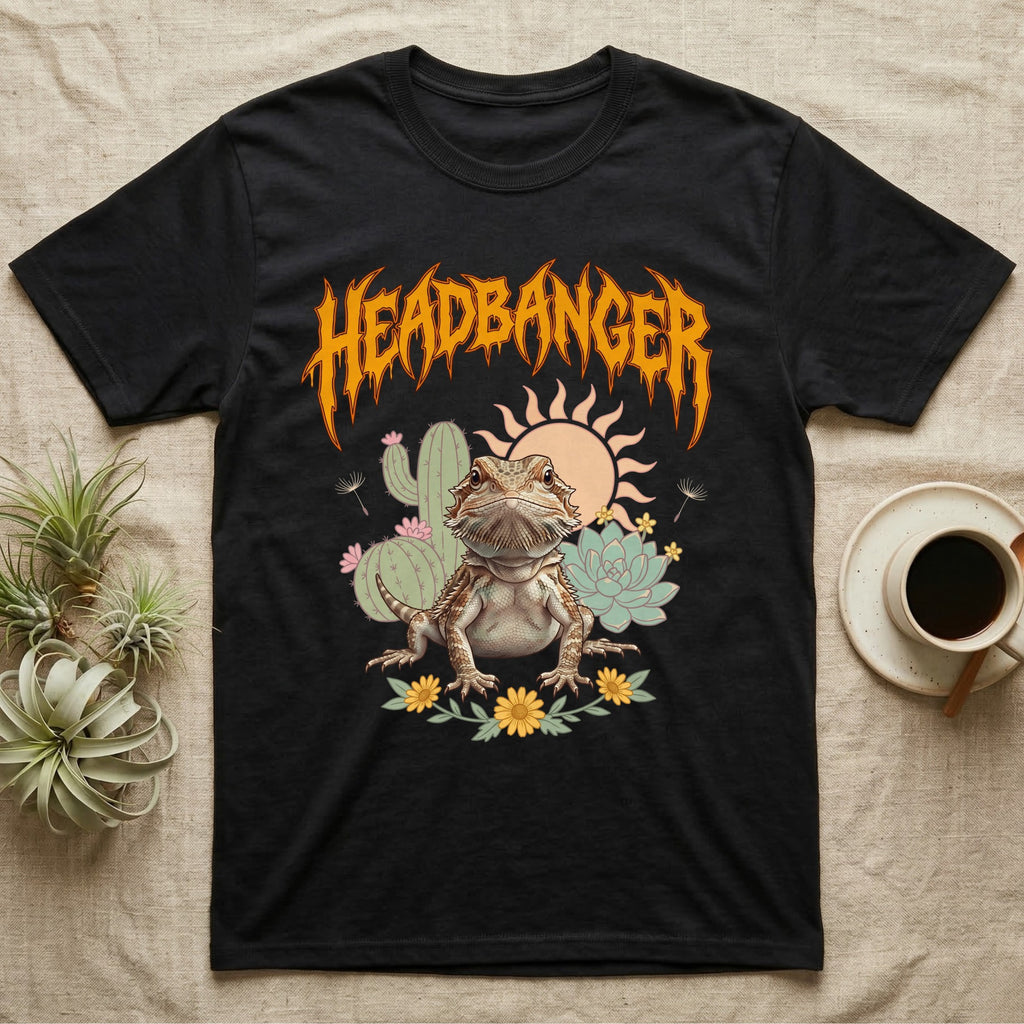 Central Bearded Dragon Feral T-Shirt in Black — Baby bearded dragon in a pastel desert scene under a spiky amber metal wordmark reading HEADBANGER.
