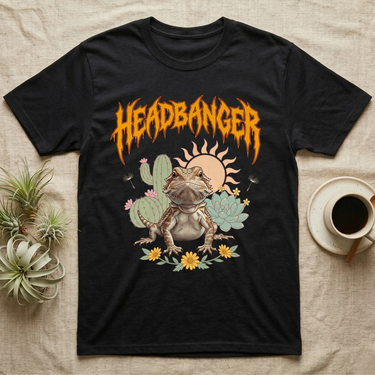 Central Bearded Dragon Feral T-Shirt in Black — Baby bearded dragon in a pastel desert scene under a spiky amber metal wordmark reading HEADBANGER.