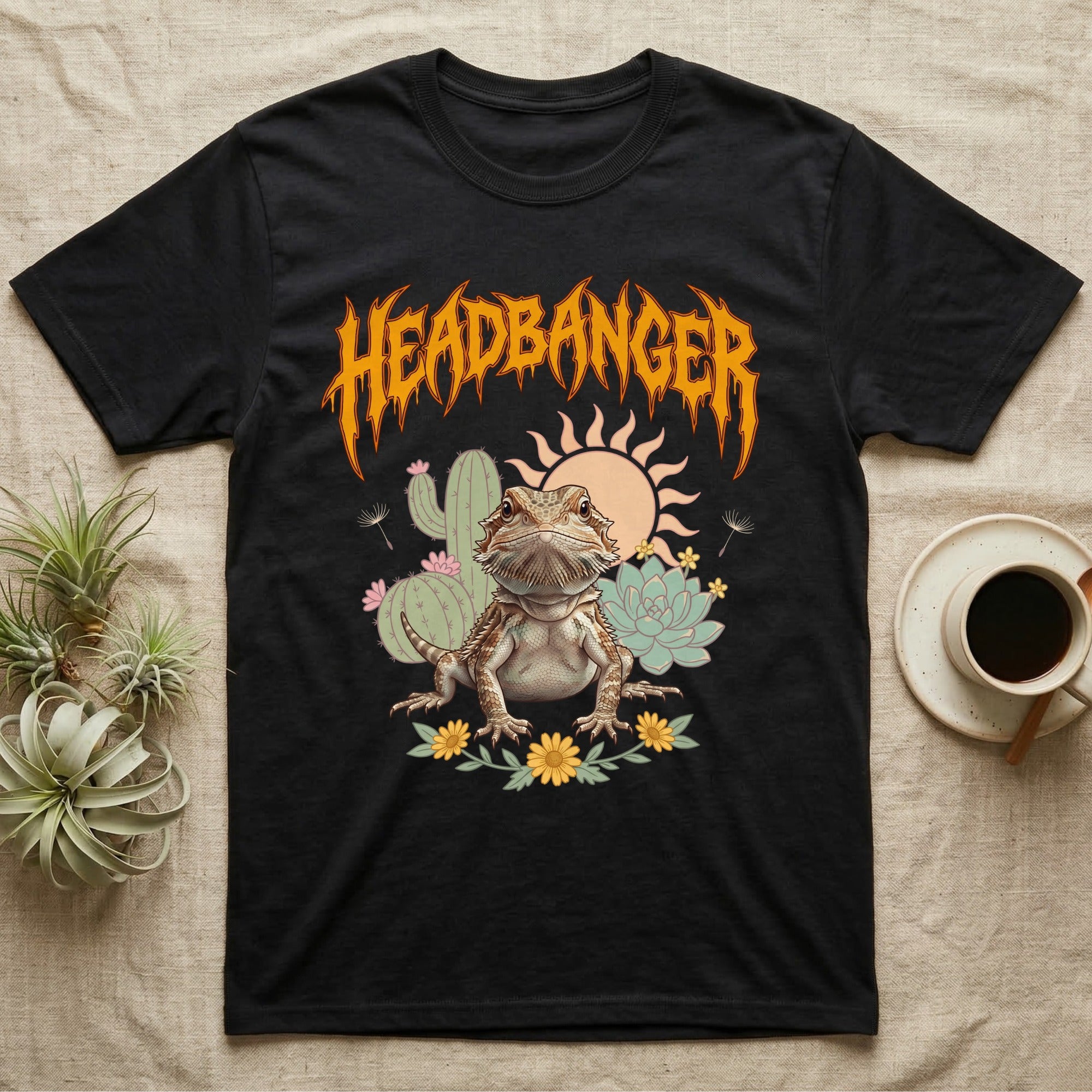 Central Bearded Dragon Feral T-Shirt in Black — Baby bearded dragon in a pastel desert scene under a spiky amber metal wordmark reading HEADBANGER.