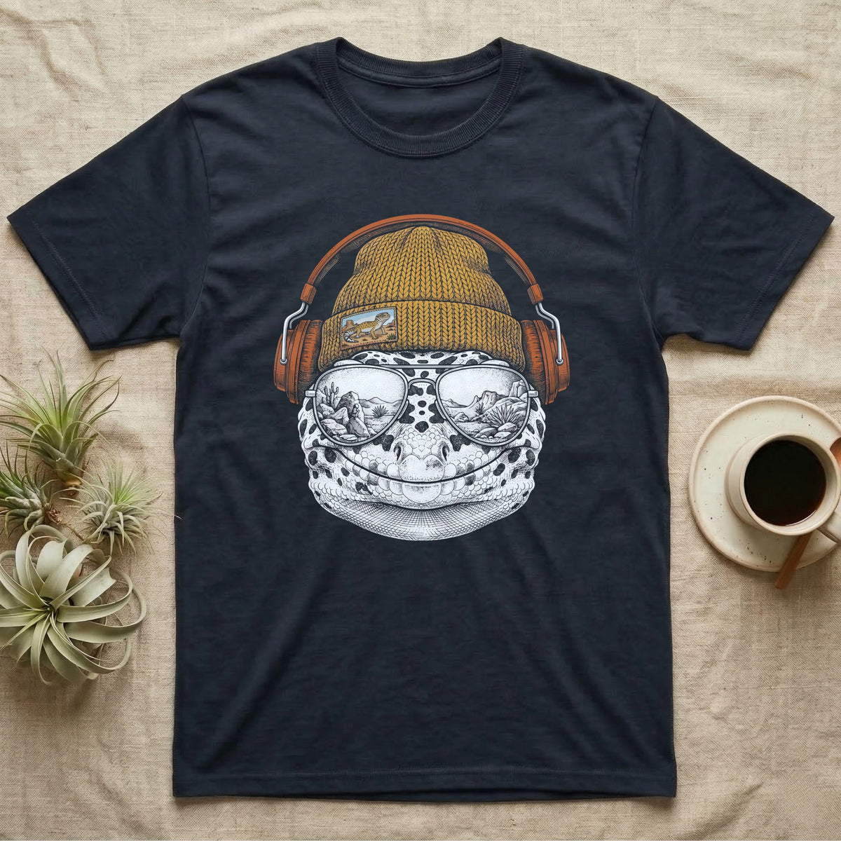 Leopard Gecko Headphones T-Shirt in Navy — Engraved leopard gecko with spotted skin in a beanie and headphones, aviators reflecting a desert canyon.