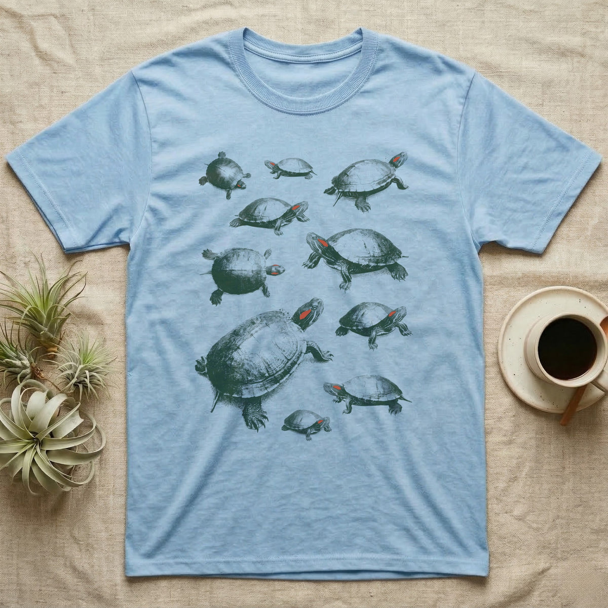 Red-Eared Slider Specimen T-Shirt in Light Blue — One red-eared slider repeated ten times in olive-green screen-print specks, each at a different size and angle, with a small red stripe behind every eye.