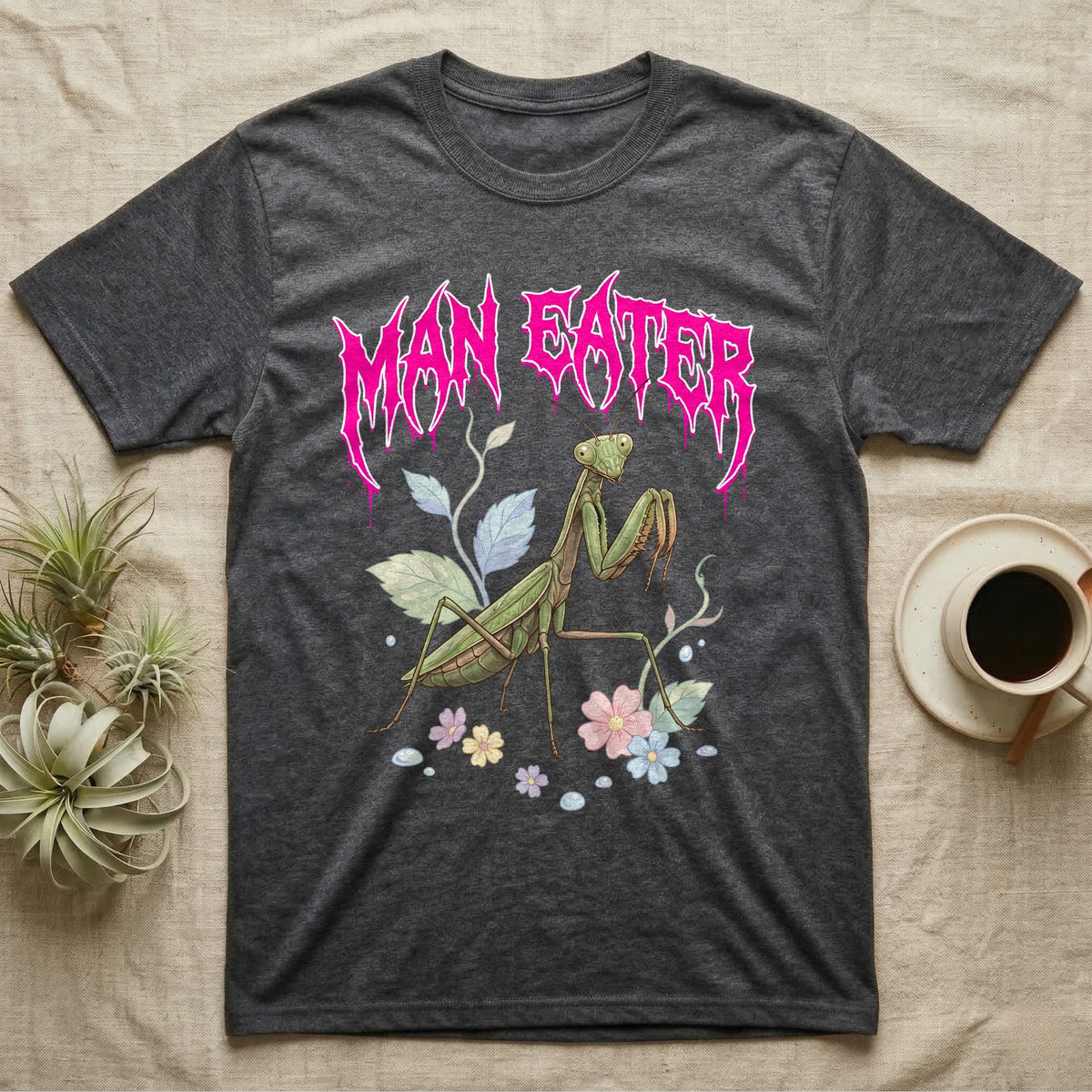Chinese Mantis Feral T-Shirt in Dark Heather — Pastel Chinese mantis with raised spiked forelegs among leaves and blossoms, jagged magenta metal wordmark "MAN EATER" above.
