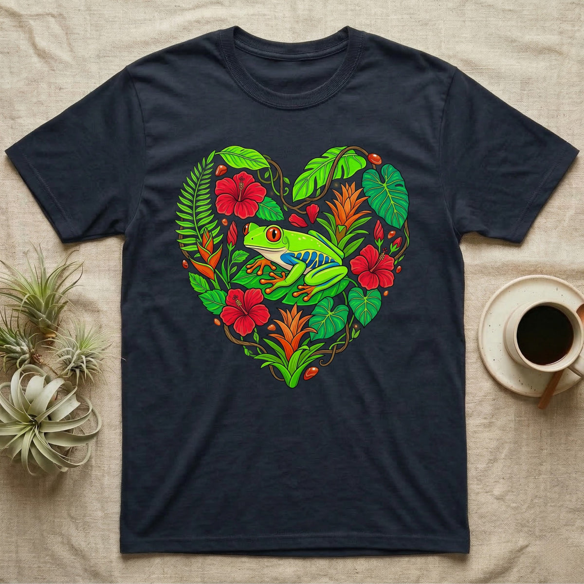 Dark t-shirt with a heart-shaped design of a green frog surrounded by tropical foliage.