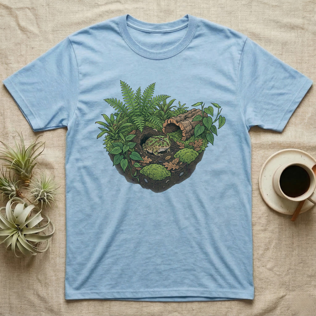 Pacman Frog Vivarium T-Shirt in Light Blue — Botanical illustration of a pacman frog thriving in a planted bioactive vivarium beside a small empty plastic cup.