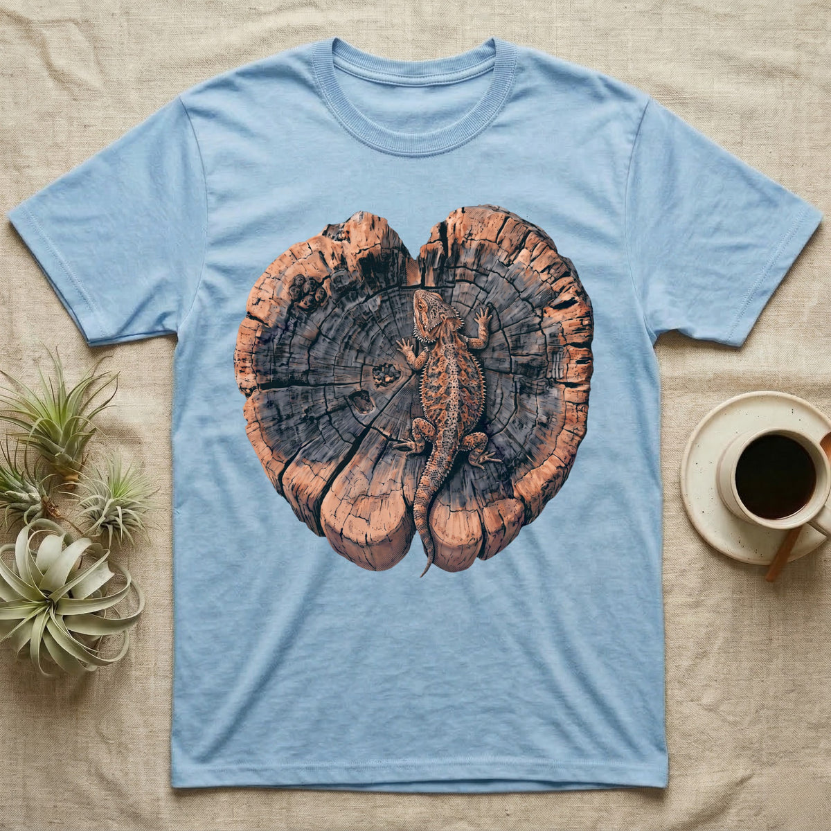 Bearded Dragon Basking Rings T-Shirt in Light Blue — Top-down illustration of a bearded dragon splayed flat on a cross-section log slab of terracotta growth rings with bracket fungus, no on-shirt text.