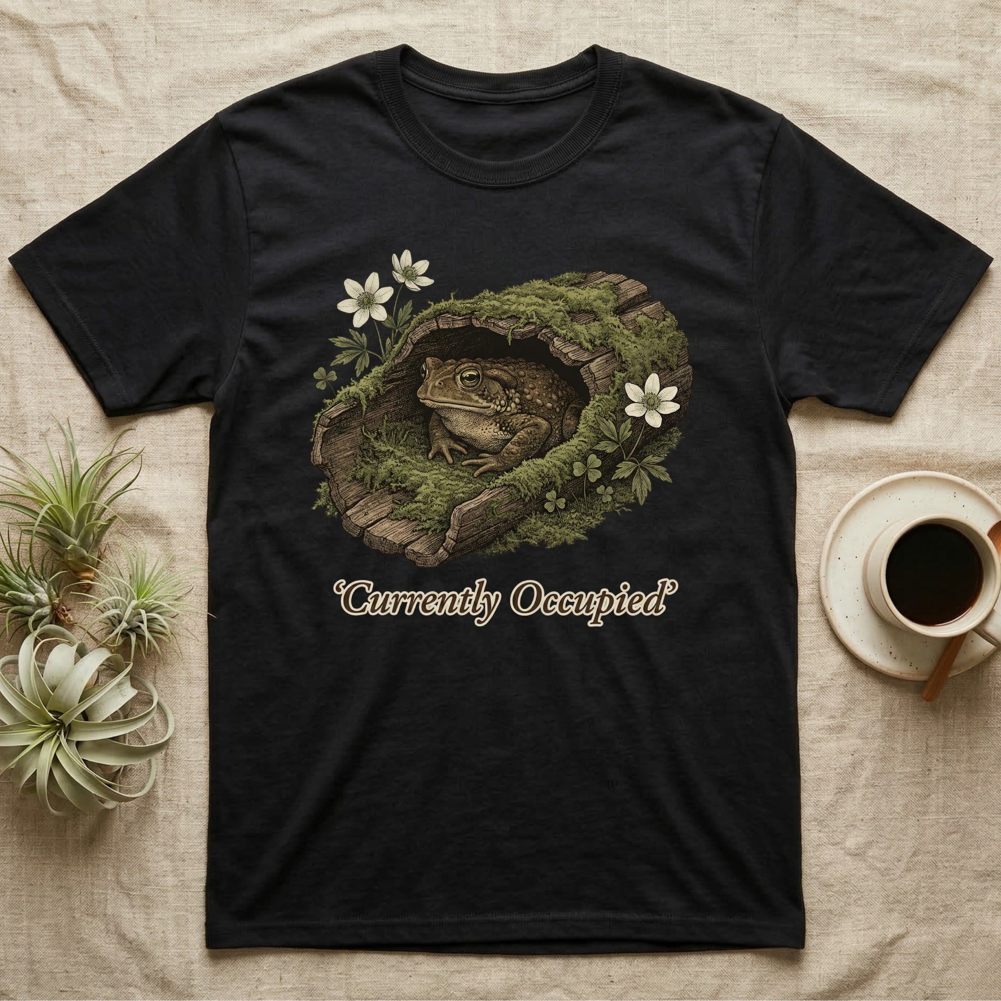 Black t-shirt with a toad inside a mossy log, text says "Currently Occupied".