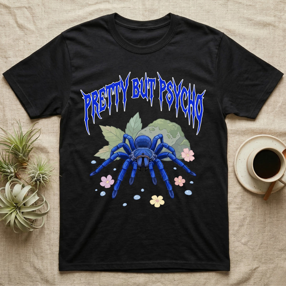 Cobalt Blue Tarantula Feral T-Shirt in Black — Cobalt blue tarantula with electric-blue legs under jagged cobalt metal text PRETTY BUT PSYCHO with pastel blossoms