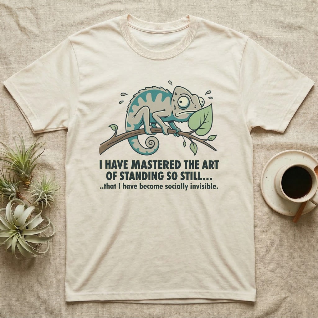 Cream t-shirt with a surprised chameleon on a branch and humorous text about invisibility.