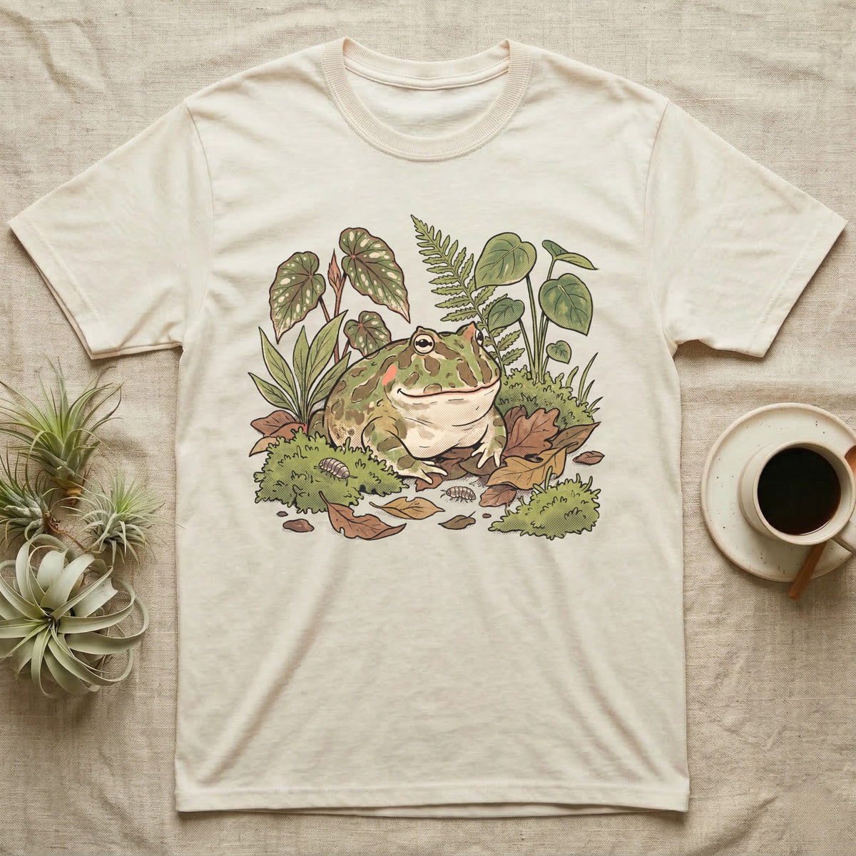 Bioactive Pacman Frog T-Shirt in Natural — Warm botanical illustration of a content pacman frog half-buried in a lush bioactive habitat of moss and leaf litter.