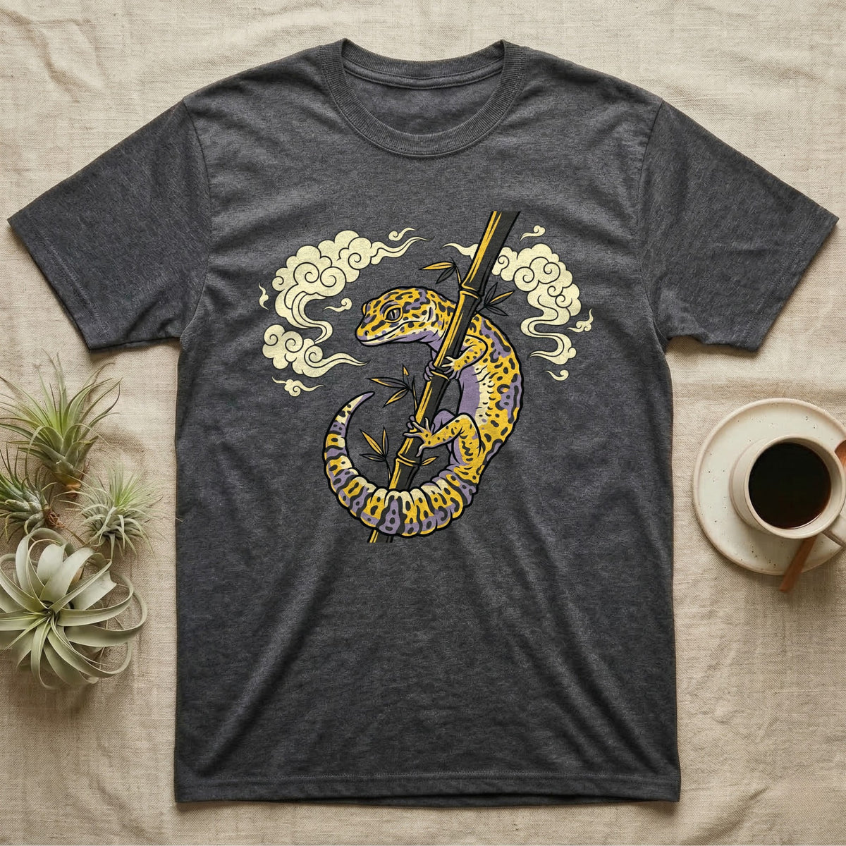 Dark grey t-shirt with a yellow and purple gecko on bamboo and clouds.