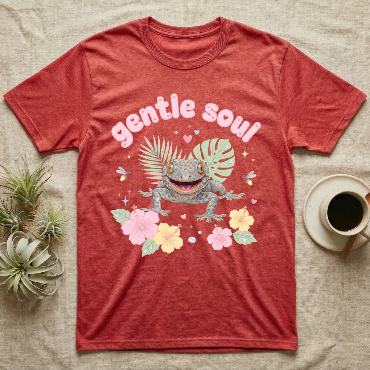 Tokay Gecko Baby T-Shirt in Heather Red — Blue-and-orange spotted tokay gecko among pastel leaves and hibiscus under puffy pink bubble text "gentle soul".