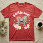 Tokay Gecko Baby T-Shirt in Heather Red — Blue-and-orange spotted tokay gecko among pastel leaves and hibiscus under puffy pink bubble text "gentle soul".