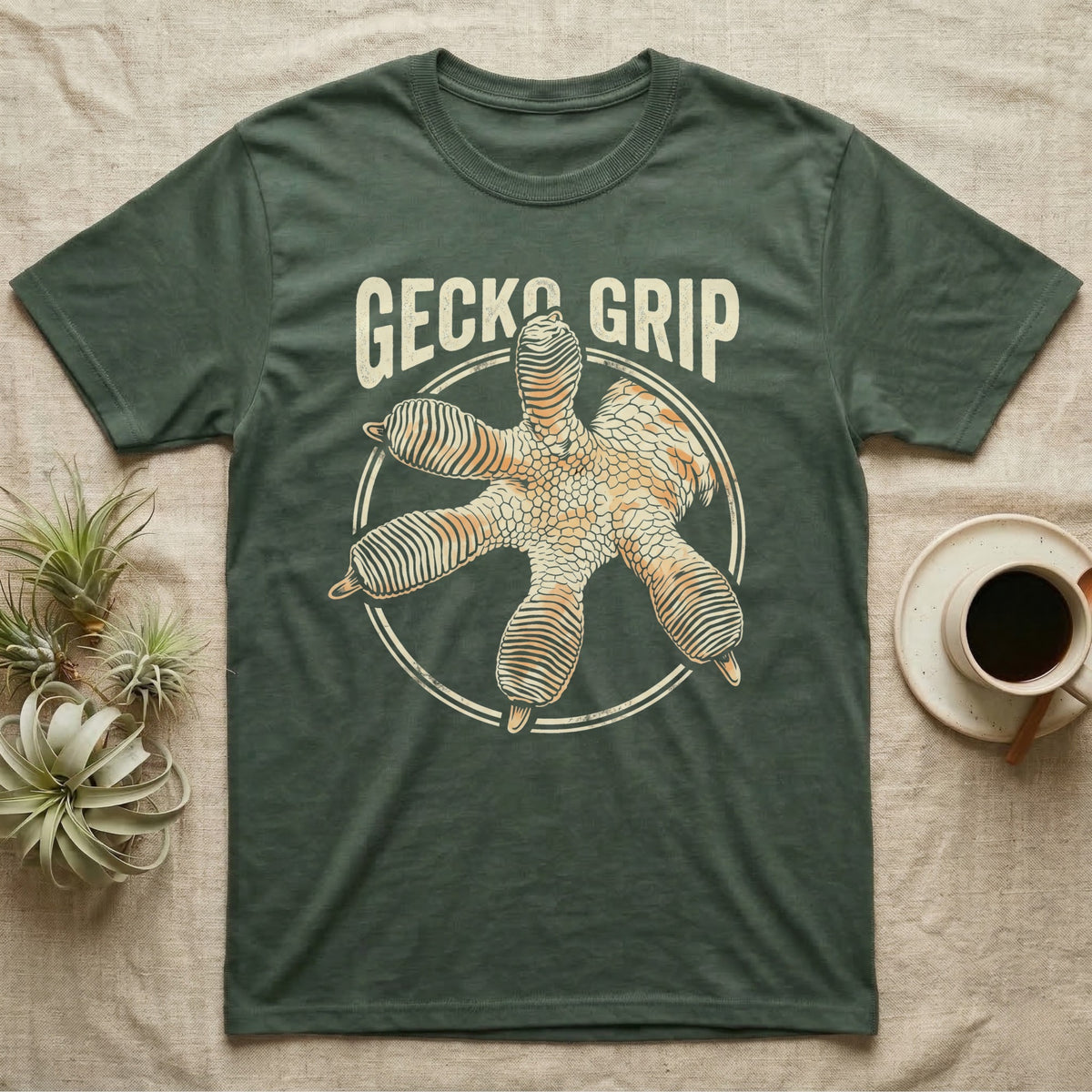 Macro badge illustration of a gecko's splayed foot with ribbed adhesive toe pads inside a distressed circular border, arched wordmark reading GECKO GRIP. — shown on a Military Green tee.