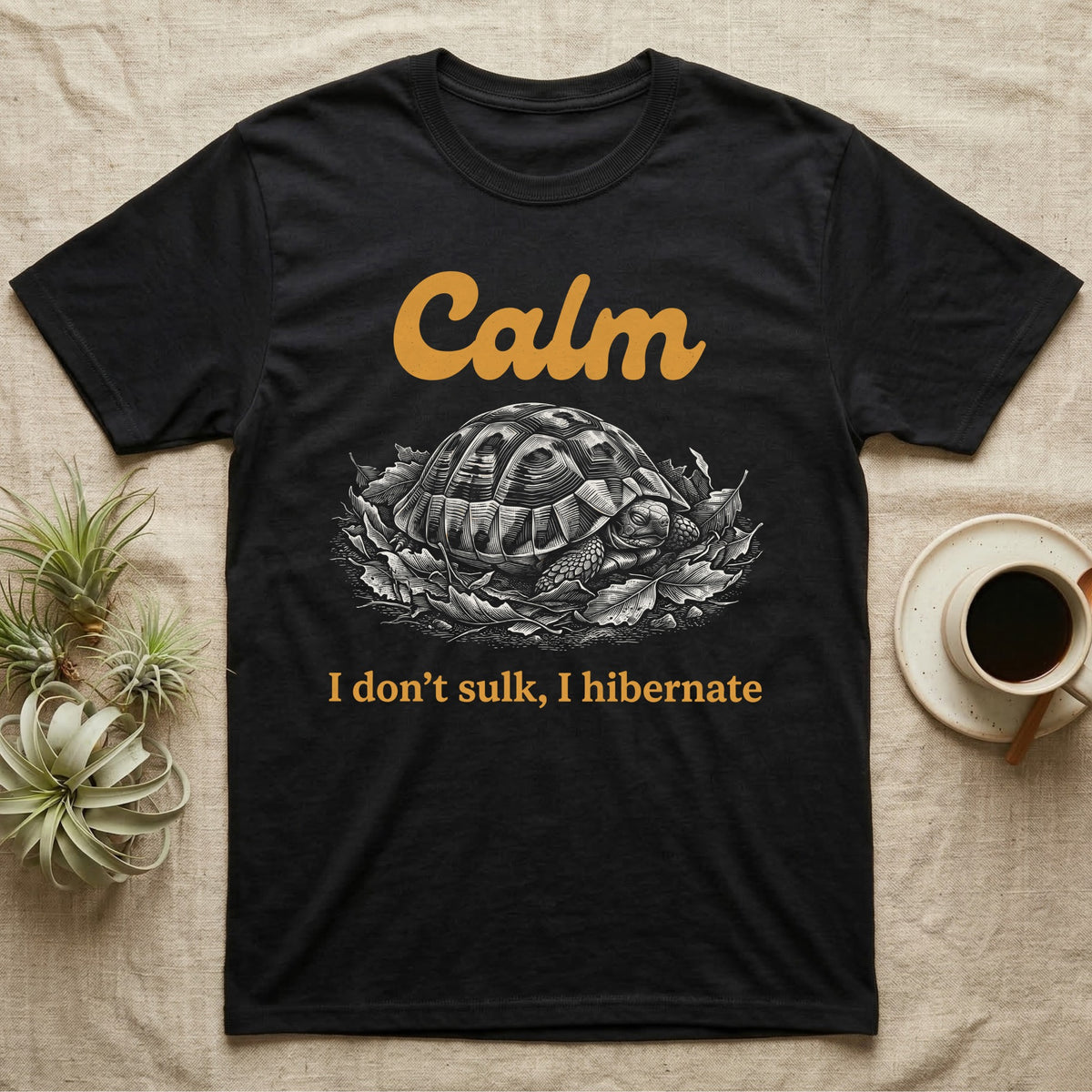 Hermann's Tortoise Calm T-Shirt in Black — White-line engraving of a Hermann's tortoise tucked into its shell in dry leaves under the word Calm