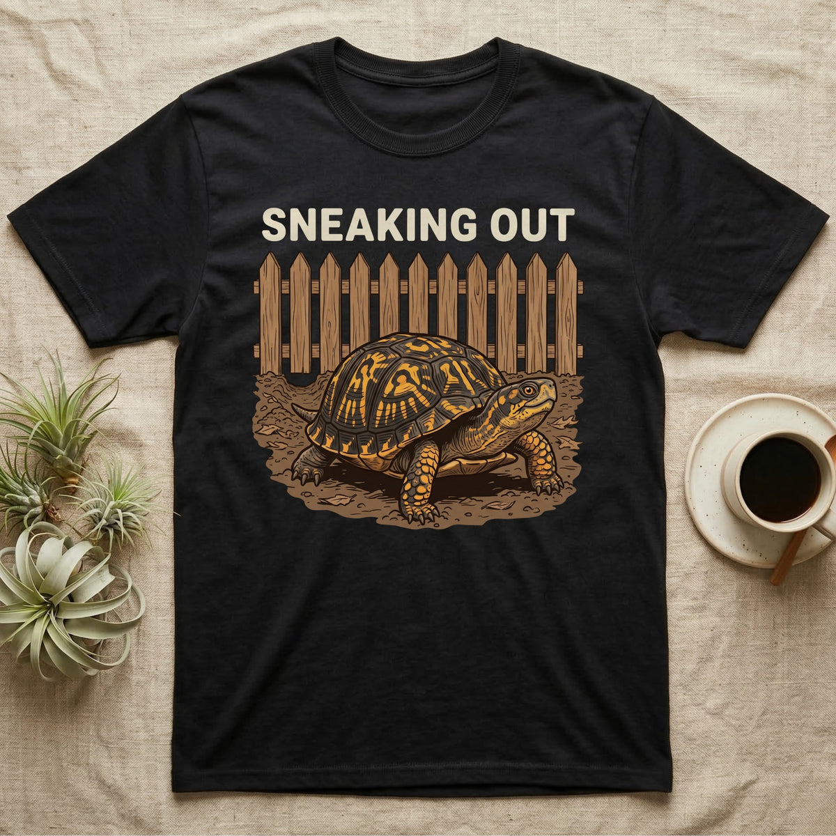 Box Turtle Sneaking T-Shirt in Black — Eastern box turtle crawling out from under a brown picket fence beneath the words Sneaking Out