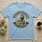 Bearded Dragon 1776 T-Shirt in Light Blue — Bold woodcut tee of a bearded dragon in a tricorn hat black-bearding on a rock, gold and cream banner reading the lizards run the economy.