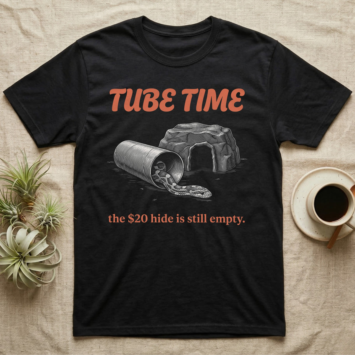 Corn Snake Tube T-Shirt in Black — Engraved corn snake lounging in a cardboard tube beside an empty rock hide, under retro script reading TUBE TIME.