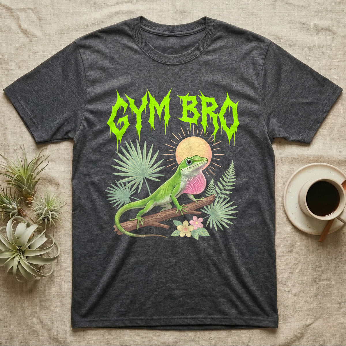 Green Anole Feral T-Shirt in Dark Heather — Green anole mid push-up with flared pink dewlap under a jagged neon-lime metal "GYM BRO" wordmark and pastel ferns.