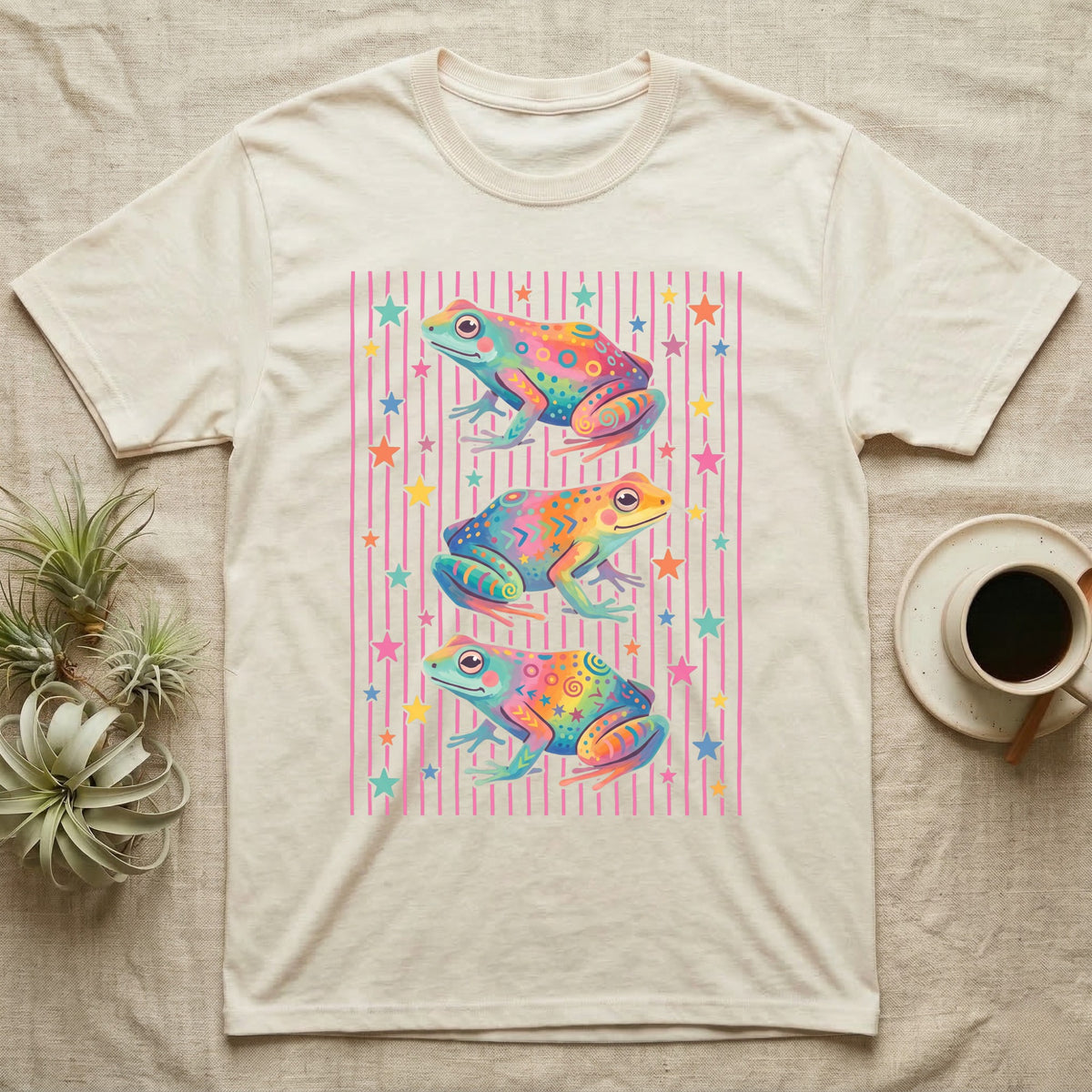 Dart Frog Disco Stripes T-Shirt in Natural — Three rainbow poison dart frog morphs stacked on a pink-and-cream candy-stripe field with scattered stars.