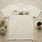 Russian Tortoise Escape Artist T-Shirt in Natural — Clean ink run-cycle illustration of a Russian tortoise escaping its wooden tortoise-table enclosure in three phases.