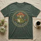 Green t-shirt with a circular graphic of a frog, mushroom, and text "Small, Damp, & Happy".