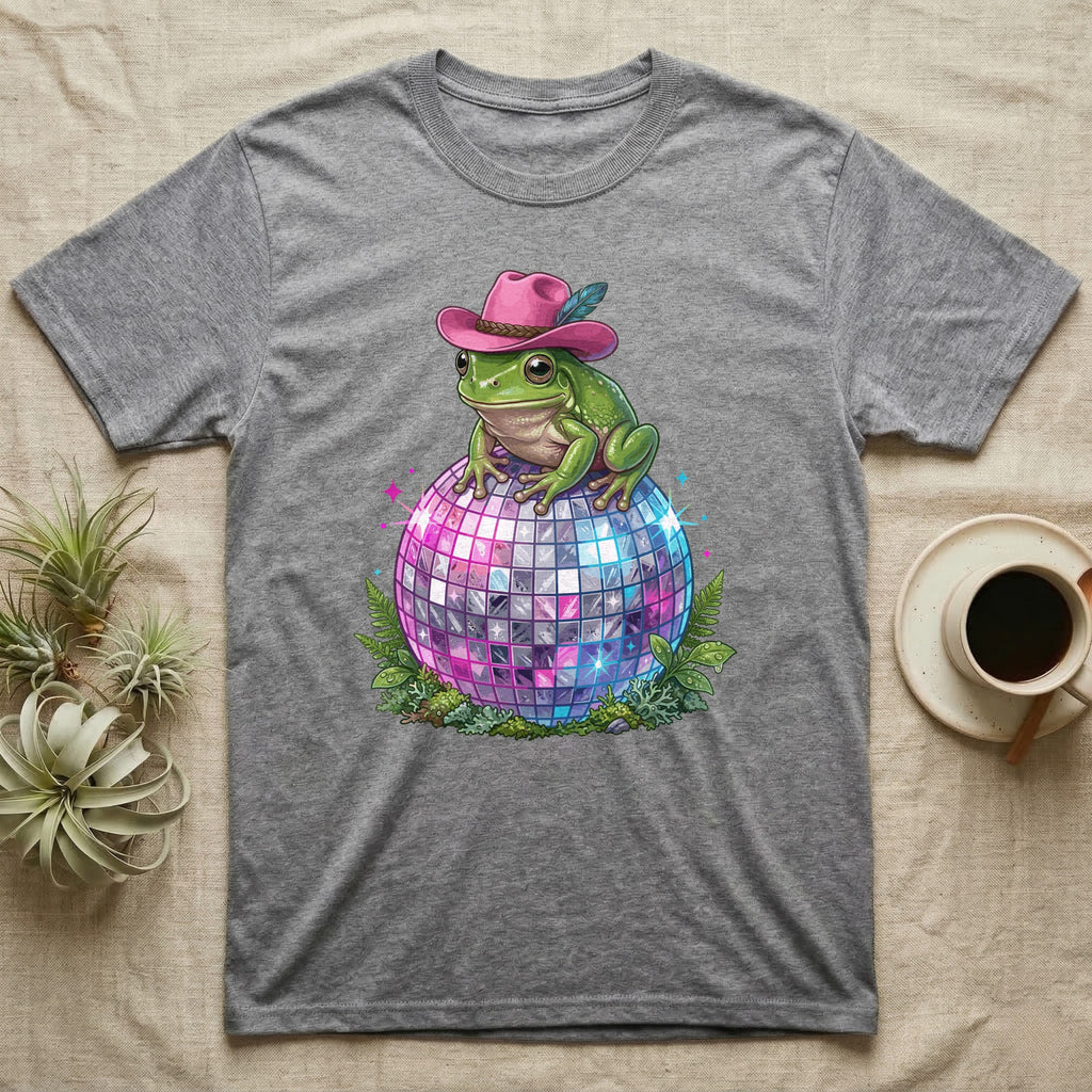 Frog wearing a pink cowboy hat sits on a disco ball with ferns.