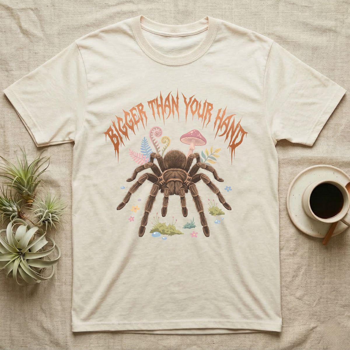 Goliath Birdeater Feral T-Shirt in Natural — Goliath birdeater tarantula with bristly legs spread under jagged copper metal text BIGGER THAN YOUR HAND